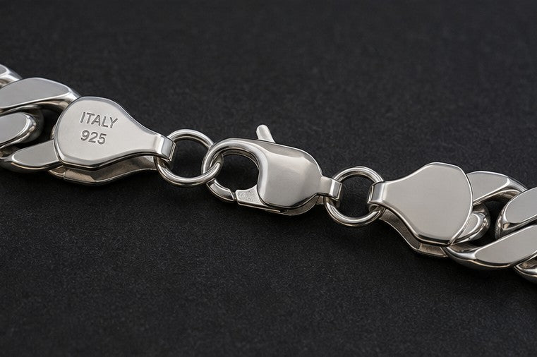 Close-up of a silver-tone metal chain bracelet with a lobster clasp, showing the engraved 'ITALY 925' hallmark on a dark textured background.