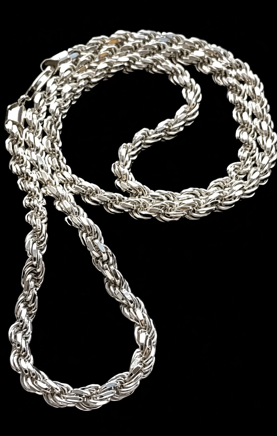 A thick silver rope chain necklace coiled on a solid black background.